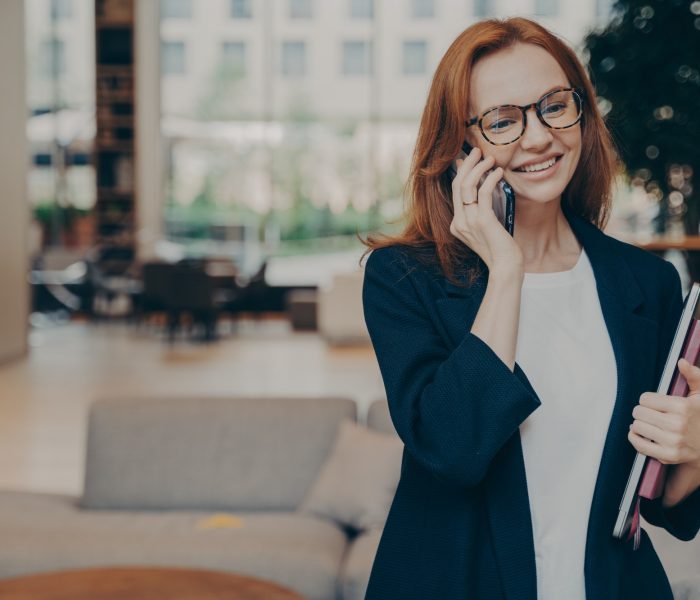 Portrait of attractive positive european business woman having mobile conversation